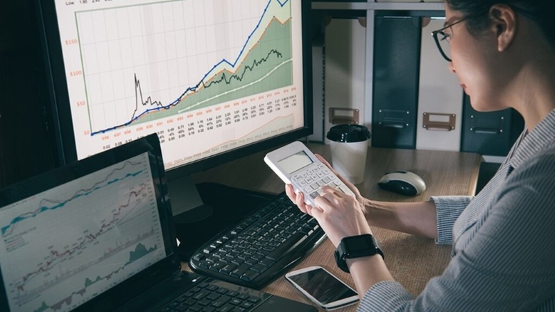 Nhà đầu tư phân tích tỷ suất cổ tức trên máy tính tại văn phòng tại nhà