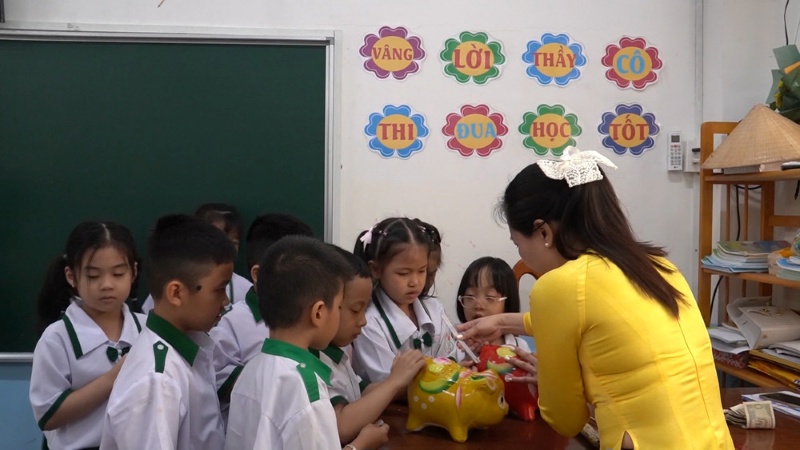 Học sinh ghi chép chi tiêu bên heo đất và ứng dụng tiết kiệm
