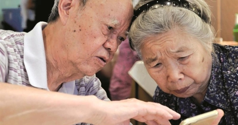 Người cao tuổi xem lại sổ tiết kiệm cùng giấy bảo hiểm tiền gửi tại nhà