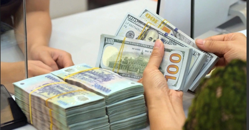 Người Việt cầm nhiều loại tiền quốc tế trên bàn gỗ